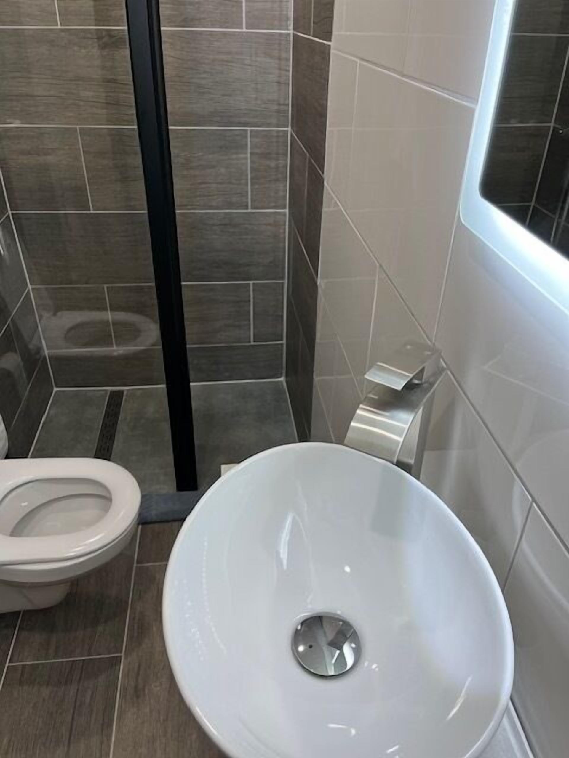 A modern bathroom with a white sink, a toilet, and a glass shower enclosure.