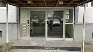 L’entrée des appartements MeisterOase, situés au 13 de la rue Weihersstraße, se distingue par une porte en verre, un petit escalier et un espace de stationnement visible à travers la porte.