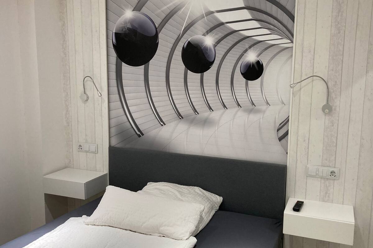 Een moderne slaapkamer met een golvend plafond, een bed met witte beddengoed en een nachtkastje met een afstandsbediening.