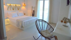 Un dormitorio con cama, una silla, un escritorio y vistas al exterior.