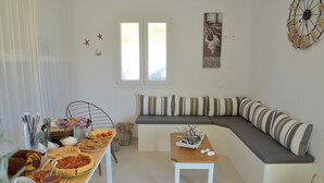 Un comedor con una mesa de buffet, un sofá con cojines a rayas y un reloj de pared decorativo.