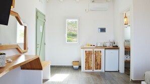 Una cocina compacta con mostrador de madera, un refrigerador pequeño y una ventana que proporciona luz natural.