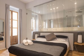 A modern bedroom with a large bed, a bedside table, a mirror, and a window with blinds. - Terrazza Sangiuliano (Catania)