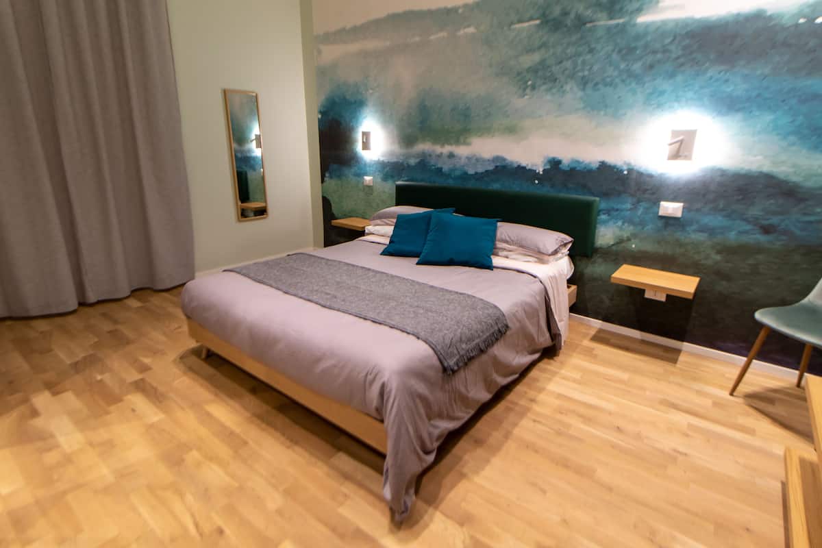 A bedroom with a bed, a nightstand, a chair, and a wall mural.