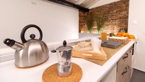 A modern kitchen with a kettle, a coffee pot, and a tray with cups and oranges. - Terrazza Sangiuliano (Catania)
