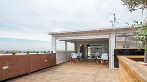A rooftop terrace with wooden flooring, white chairs, and a view of the sea. - Terrazza Sangiuliano (Catania)