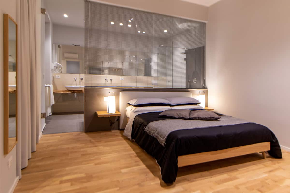 A modern bedroom with a wooden bed, bedside tables, and a large mirror.
