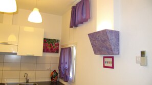 A kitchen with white cabinets, a sink, and a window with purple curtains.