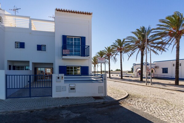 Ein modernes Gebäude mit weißer Fassade und blauen Akzenten, ausgestattet mit Balkonen und einem verschlossenen Eingang.