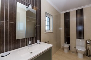 Ein modernes Badezimmer mit großem Spiegel, Waschbecken, integriertem Bidet und Toilette.