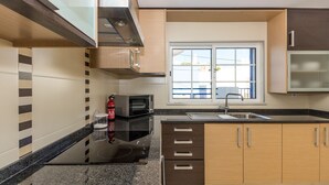 Una cocina moderna con microondas, estufa y pileta integrados. Hay una ventana que proporciona luz natural y vistas al exterior.