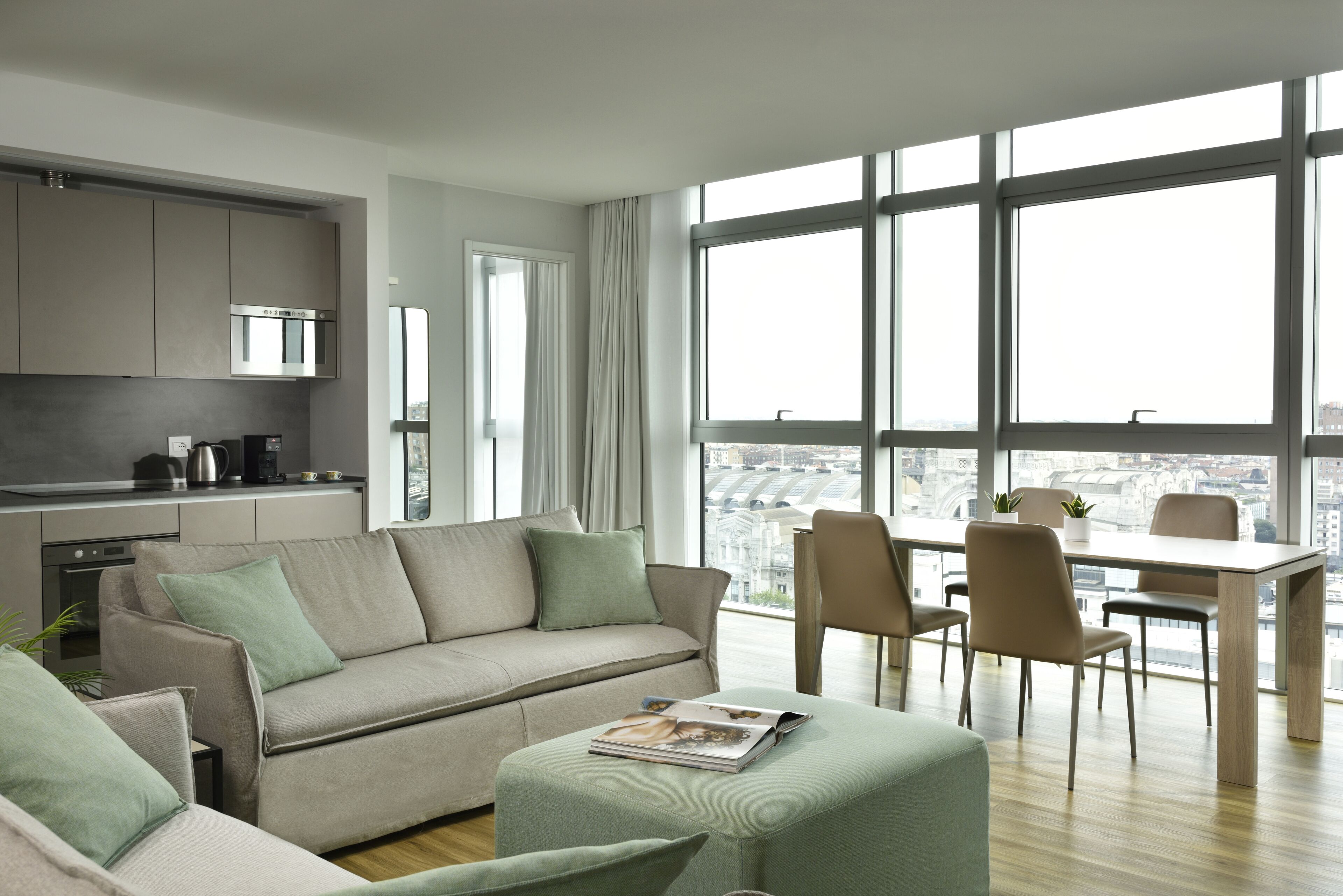 Uma sala de estar moderna com sofá, apoio para os pés e área de jantar.