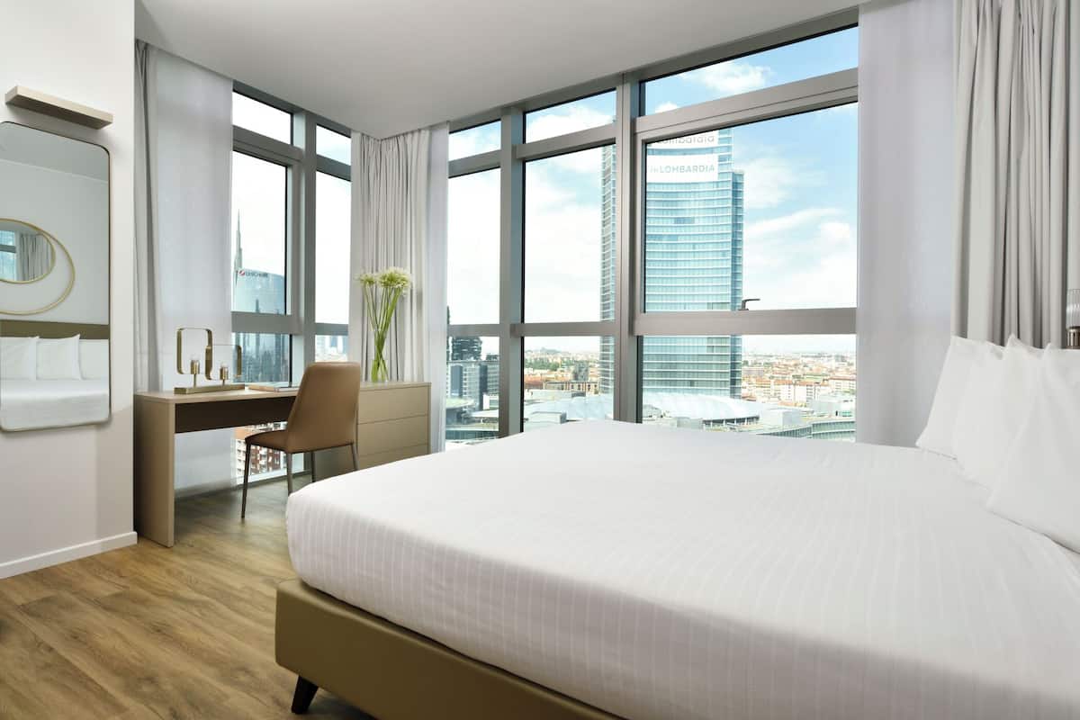 Una habitación de hotel moderna con una cama grande, un escritorio y una silla.