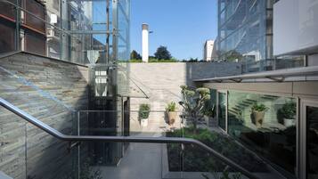 Un edificio moderno con facciata in vetro, una scala interna e una piccola area giardino con piante in vaso.