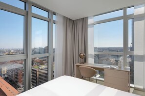 Une chambre d’hôtel moderne dotée d’une grande fenêtre, d’un bureau et d’une chaise.