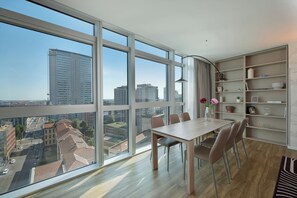 Un appartement moderne doté d’un grand balcon, d’un coin repas avec une table et des chaises, et d’une bibliothèque.