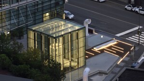Un edificio moderno con fachada de vidrio y un paso de peatones con líneas iluminadas.