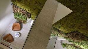 Un interior moderno con una pared verde, un panel blanco grande y dos sillas marrones con una mesita.