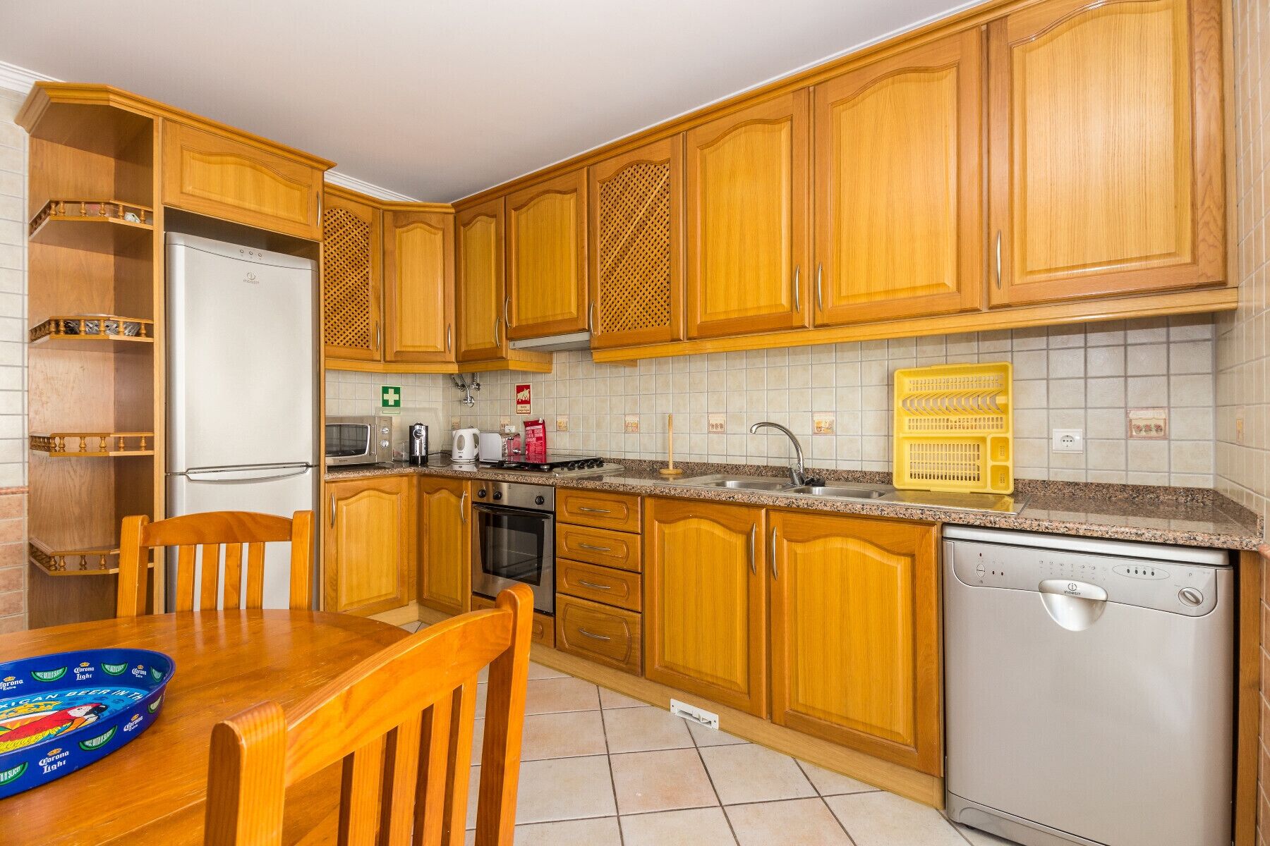 Una cocina con gabinetes de madera, refrigerador, estufa, pileta y lavavajillas.