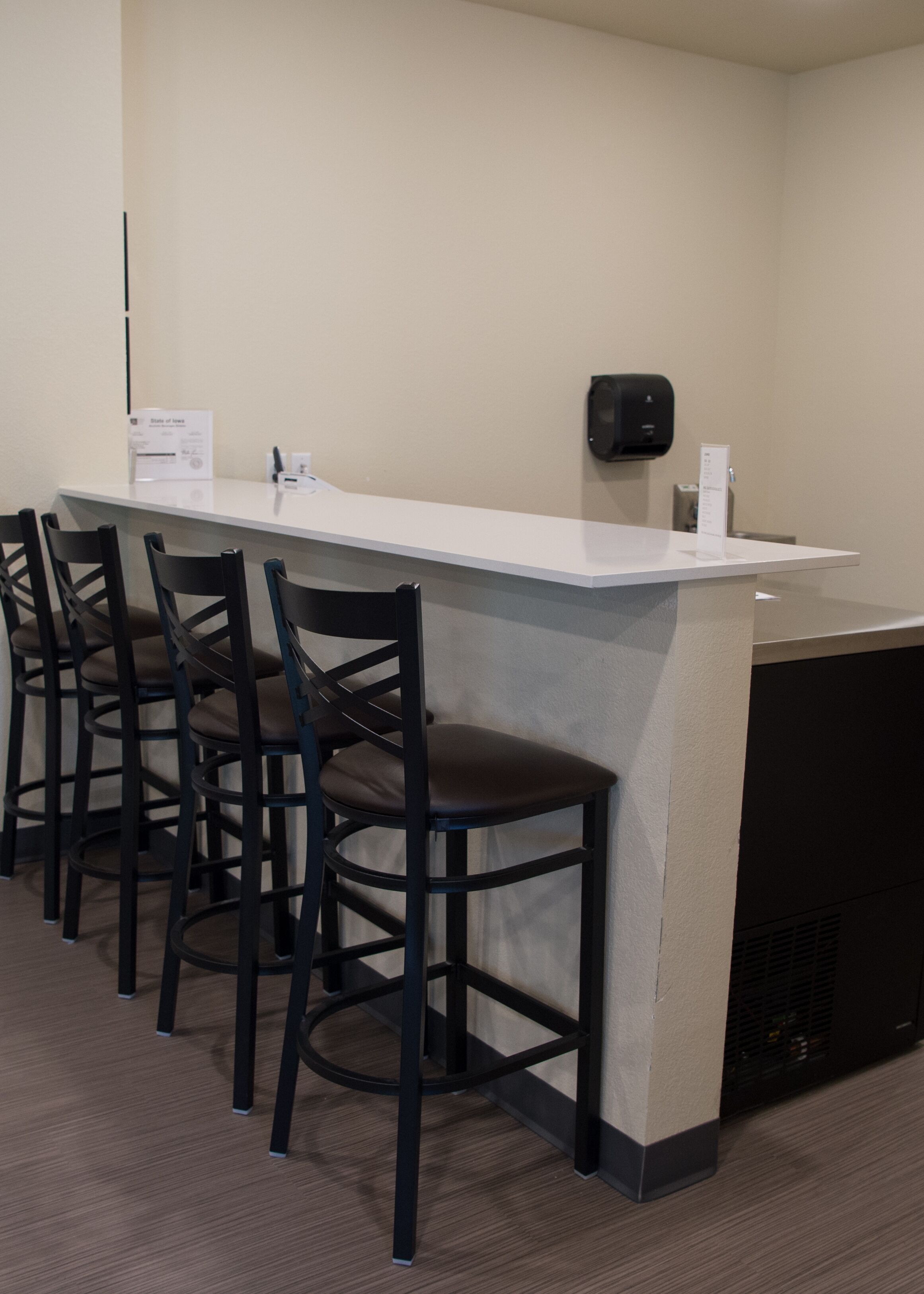 A bar area with a white counter and three black bar stools.
