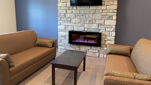 Una sala de estar con chimenea de piedra, un televisor de pantalla plana montado encima y dos sofás marrones.