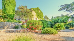 Ein Haus mit einer Steinmauer und einem Garten mit verschiedenen Pflanzen und Blumen.