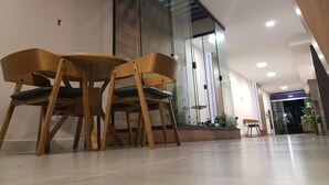 Un interior moderno con un separador de vidrio, sillas de madera y suelo de baldosas.