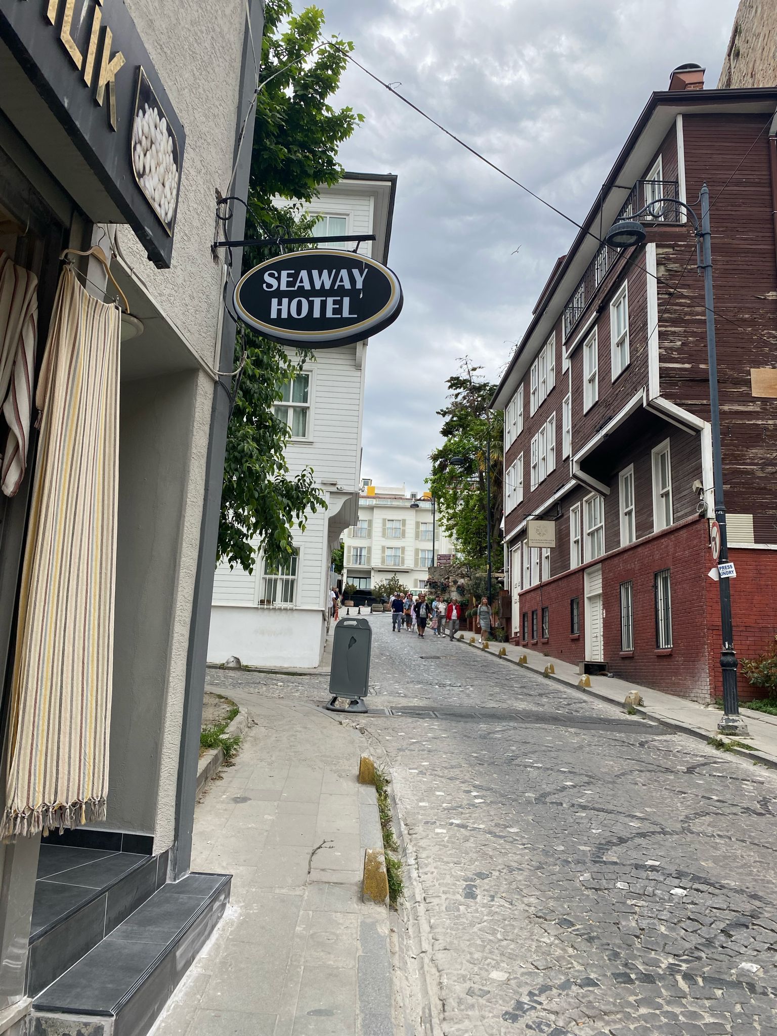 A street view with a hotel sign, buildings, and a cobblestone street.