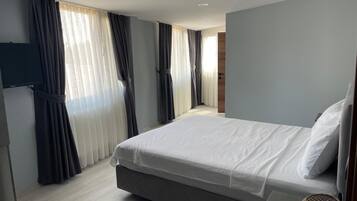 Een moderne hotelkamer met een groot bed, een flatscreen televisie aan de muur en uitzicht op de gang.