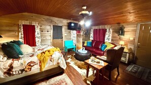 Ett mysigt rum med en säng, en soffa, ett litet bord och en tv.