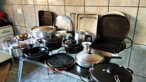 Een keuken met diverse kookgerei en apparaten, waaronder potten, pannen, een grill en een fornuis.