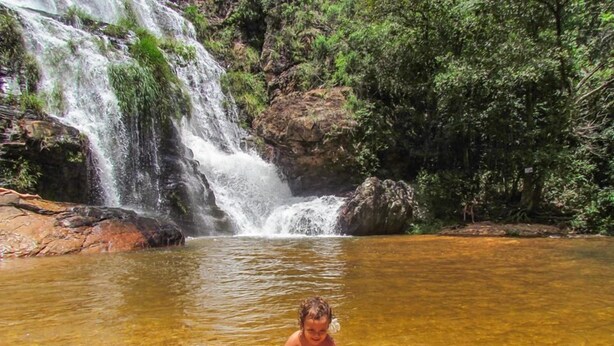 Een waterval in een natuurlijke omgeving, met helder water en rotsen onderin.