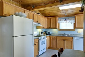 Una cocina con gabinetes de madera, un refrigerador, estufa y lavavajillas.