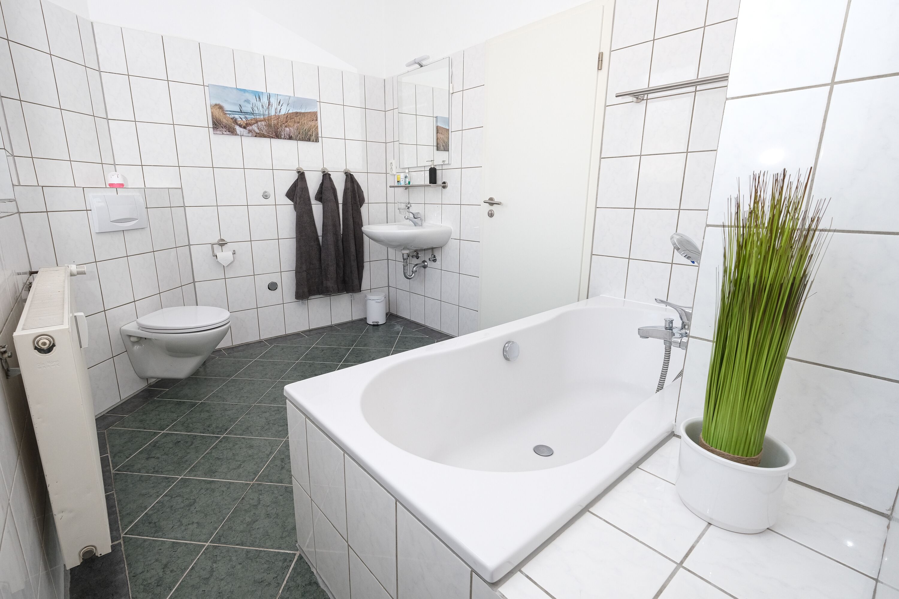 Een moderne badkamer met een bad, toilet en wastafel.