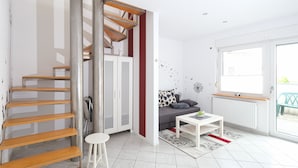 A modern apartment with a spiral staircase, a sofa, a coffee table, and a large window. - Apartment mit Wohnflair (Essen)