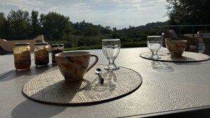 A table set with two cups, two glasses, and two jars of jam.