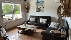 A cozy living room with a leather sofa, a coffee table, and a painting of boats.