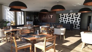 A restaurant with wooden tables and chairs, black pendant lighting, and a 'SALT RESTAURANT' sign. - 32  Bay View Suites  (Langstrand)