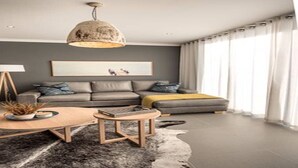 A modern living room with a grey sofa, a wooden coffee table, and a round side table. - 32  Bay View Suites  (Langstrand)