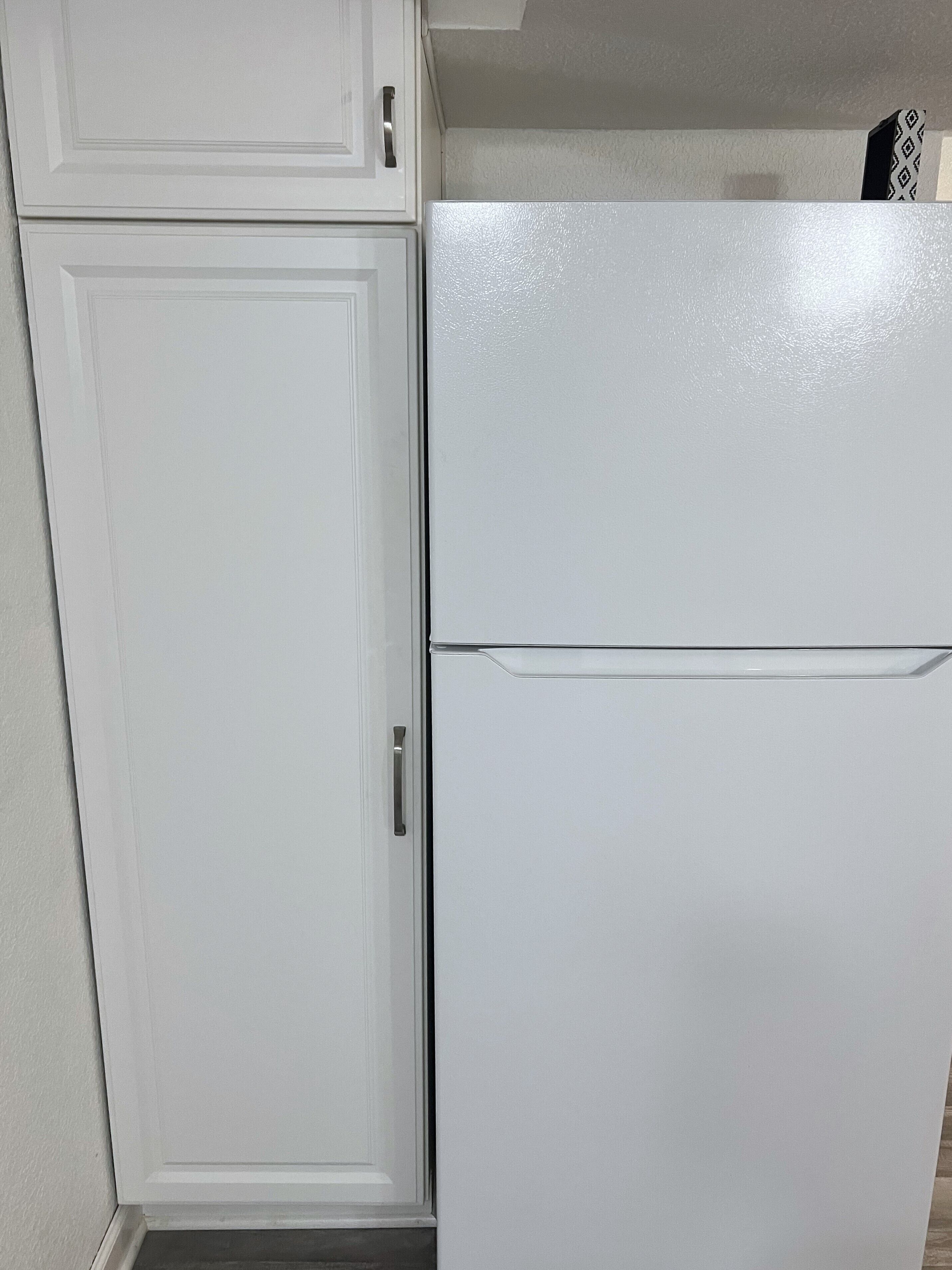 A kitchen with white cabinetry and a white refrigerator.