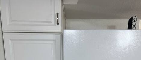 A kitchen with white cabinetry and a white refrigerator.