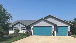 Une maison à deux étages avec un garage, un petit porche et une pelouse bien entretenue.