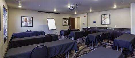 A conference room with tables, chairs, a whiteboard, and a projector.
