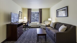 A hotel room with a desk, chair, couch, and a TV. - Cobblestone Inn & Suites - Brookville (Brookville)