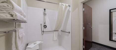 A modern bathroom with a walk-in shower, a toilet with a towel rack, and a door leading to another room.