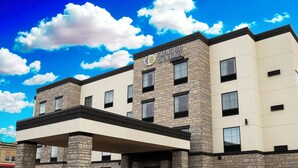 A hotel with a stone facade, a covered entrance, and a parking lot. - Cobblestone Hotel & Suites - Two Rivers (Two Rivers)
