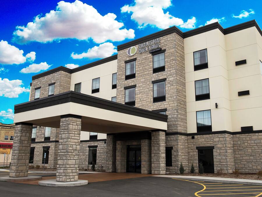A hotel with a stone facade, a covered entrance, and a parking lot.