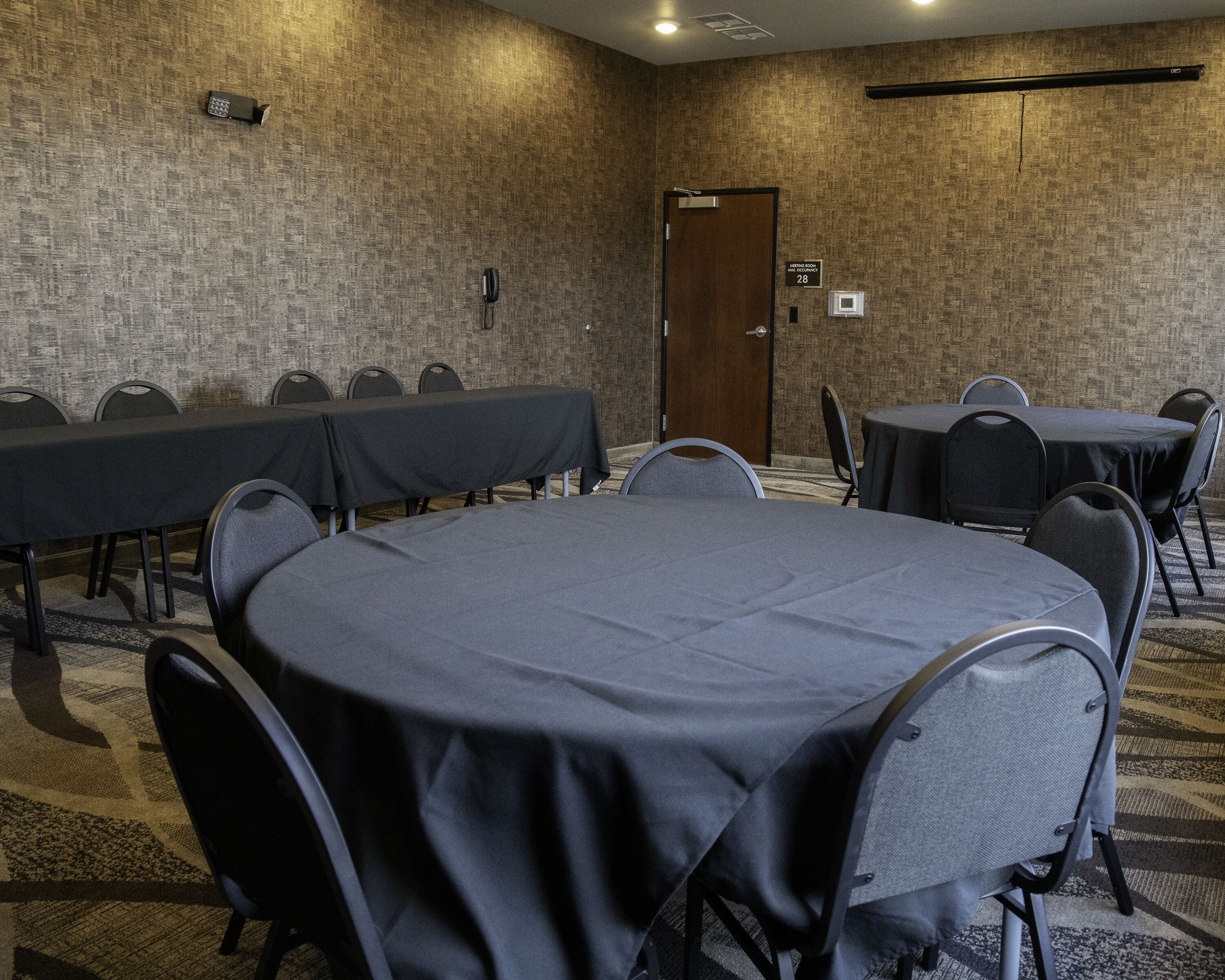 A conference room with a large round table and several smaller tables, equipped with chairs.