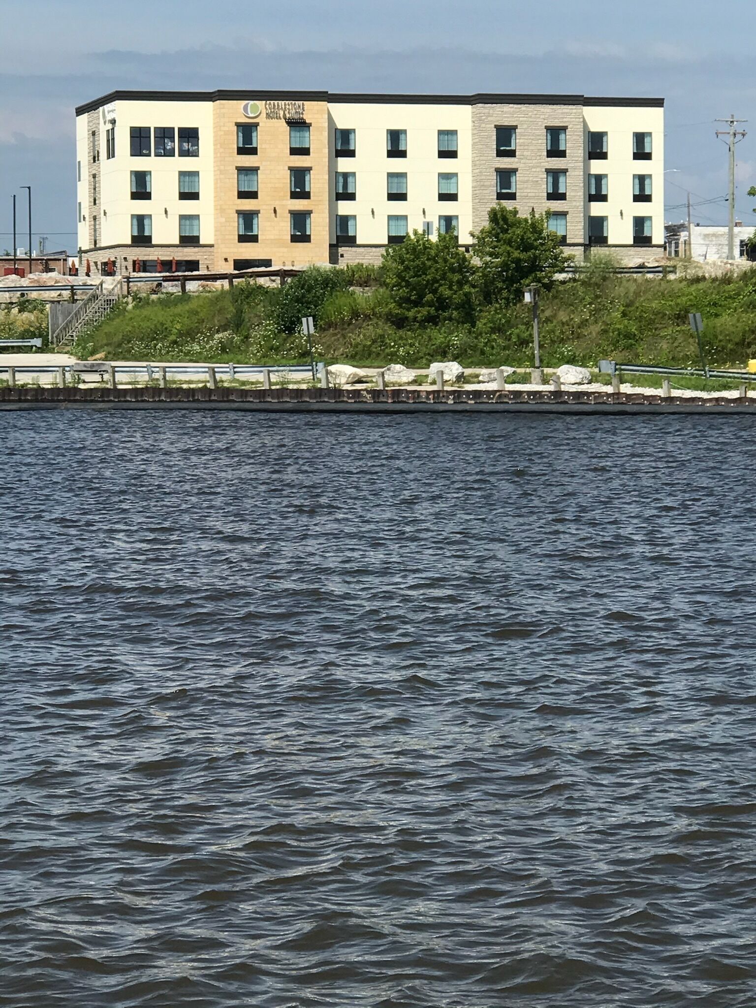 Un hotel de varios pisos con techo plano, situado junto a una masa de agua.