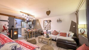 Ein gemütliches Wohnzimmer mit Kamin, einer Couch, einem Couchtisch und einem Essbereich mit Stühlen und Tisch.
